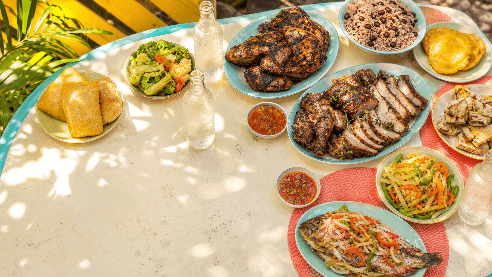A bright outdoor spread of Jamaican jerk dishes and sides — concept photography